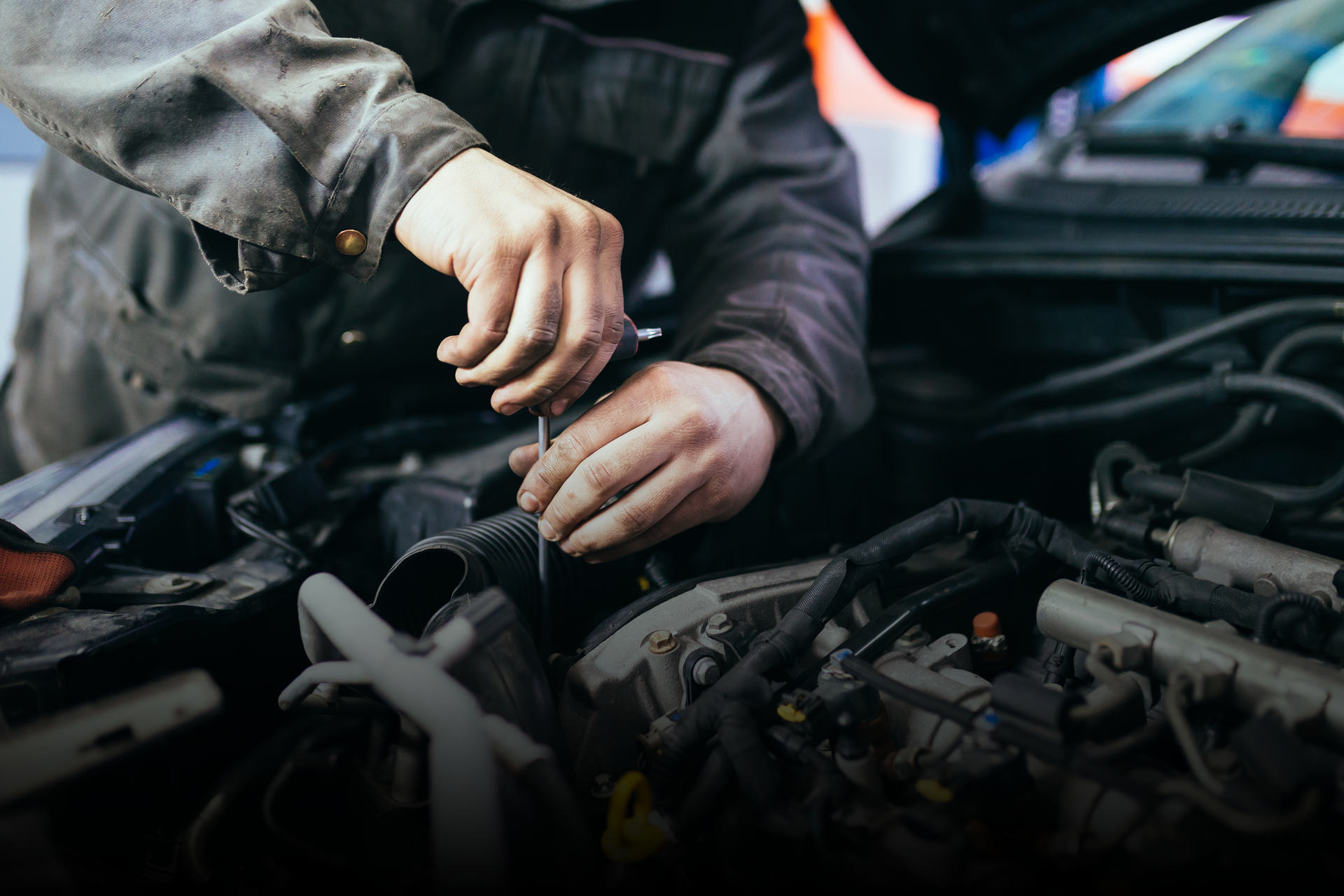 Mechanic inspecting engine components under the hood at an auto repair shop