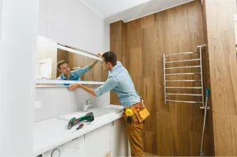 Workman installing medicine cabinet in bathroom with wood paneling bathroom remodel  company Huntington Beach 