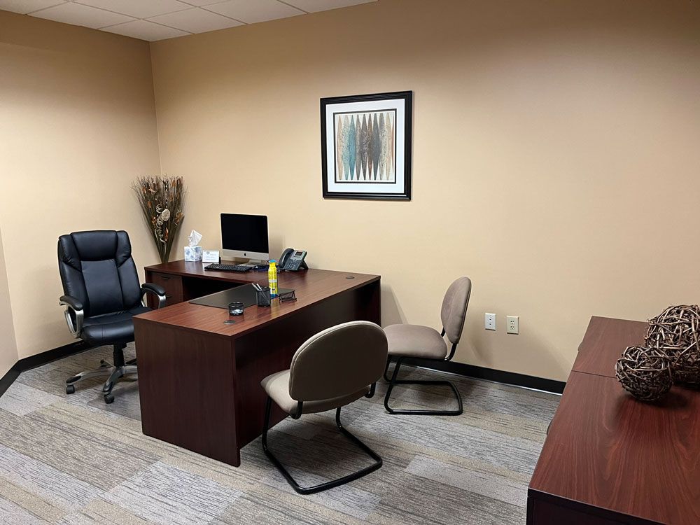A small office with a desk , chairs and a computer.