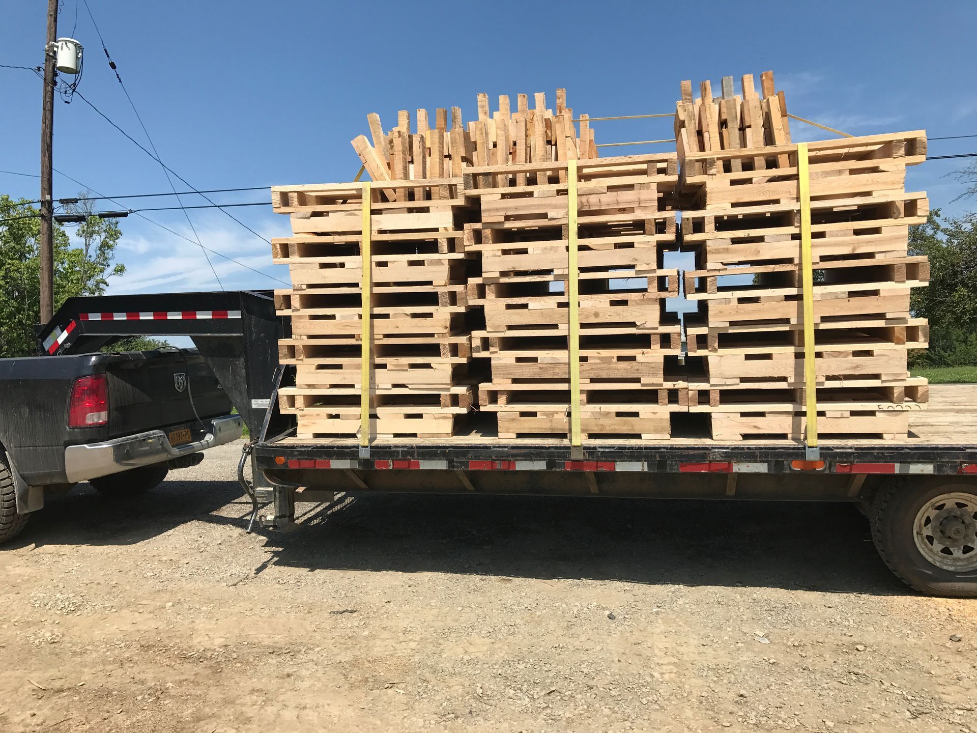 A truck is pulling a trailer full of wooden pallets.