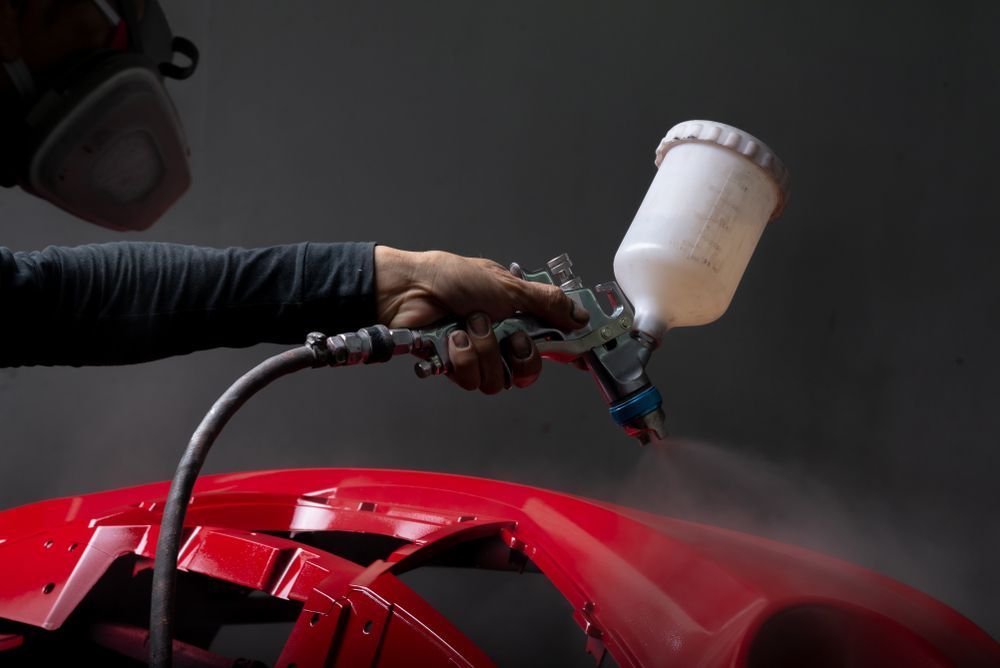 A Person Wearing a Respirator Sprays Bright Red Paint — Best Car Detailing in Vincent, QLD
