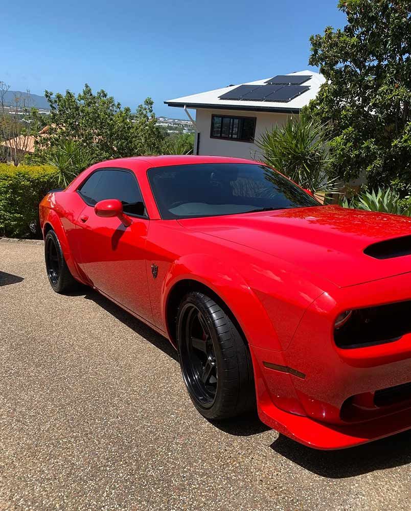 A Red Dodge Challenger is Parked in Front of a House — Best Car Detailing in Vincent, QLD
