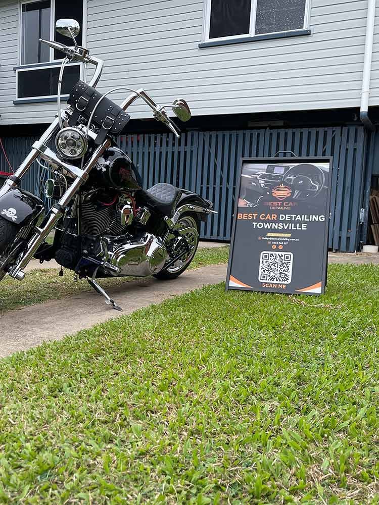 A Motorcycle is Parked in Front of a House Next to a Sign — Best Car Detailing in Vincent, QLD