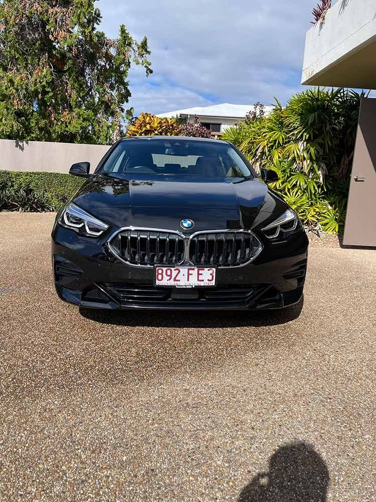 A Black BMW is Parked in a Driveway in Front of a House — Best Car Detailing in Vincent, QLD