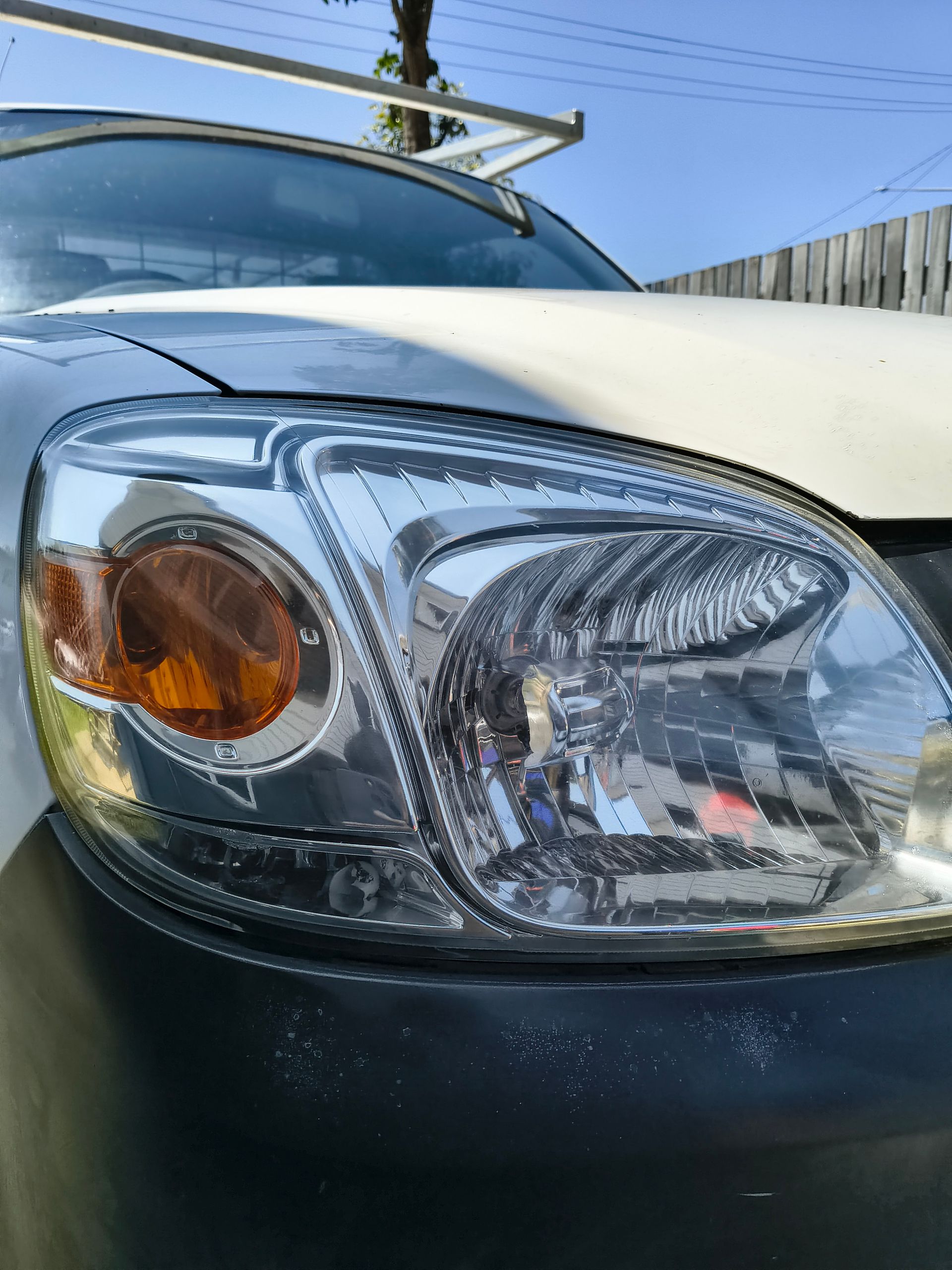 Close-up Of A Car Headlight, Showing The Amber Turn Signal And Main Light Assembly, On A White Vehicle — Best Car Detailing in Vincent, QLD