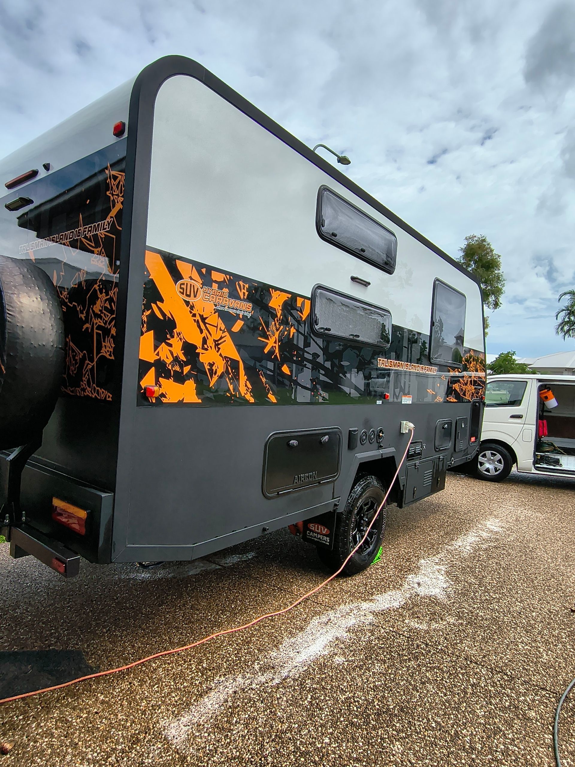 Gray And Black Travel Trailer With Orange Accents Parked Outdoors On Gravel — Best Car Detailing in Vincent, QLD
