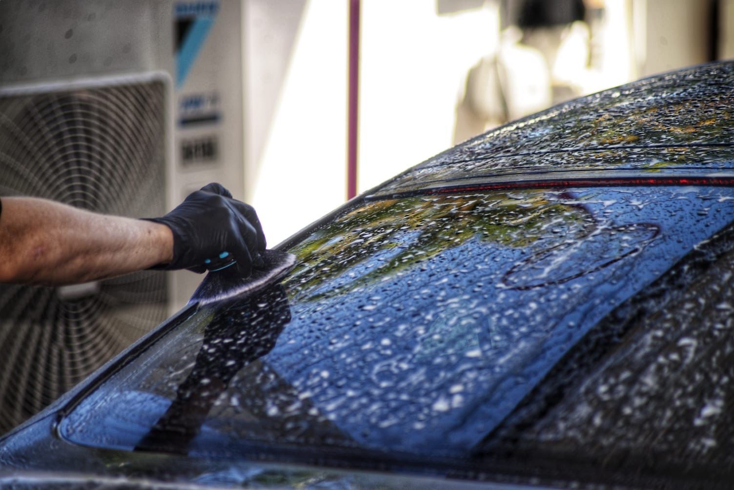 A Person is washing the front windscreen of a black car— Best Car Detailing in Vincent, QLD