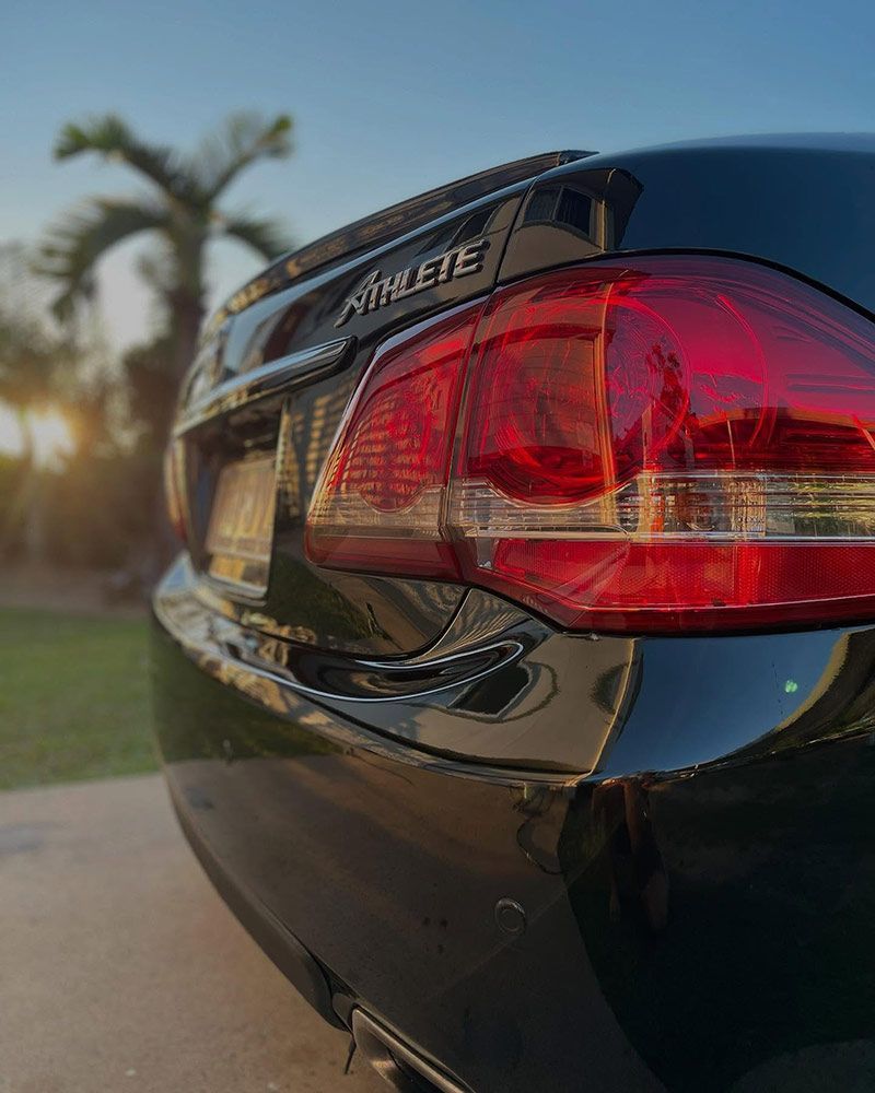 A Black Car With a Red Tail Light is Parked on the Side of the Road — Best Car Detailing in Vincent, QLD