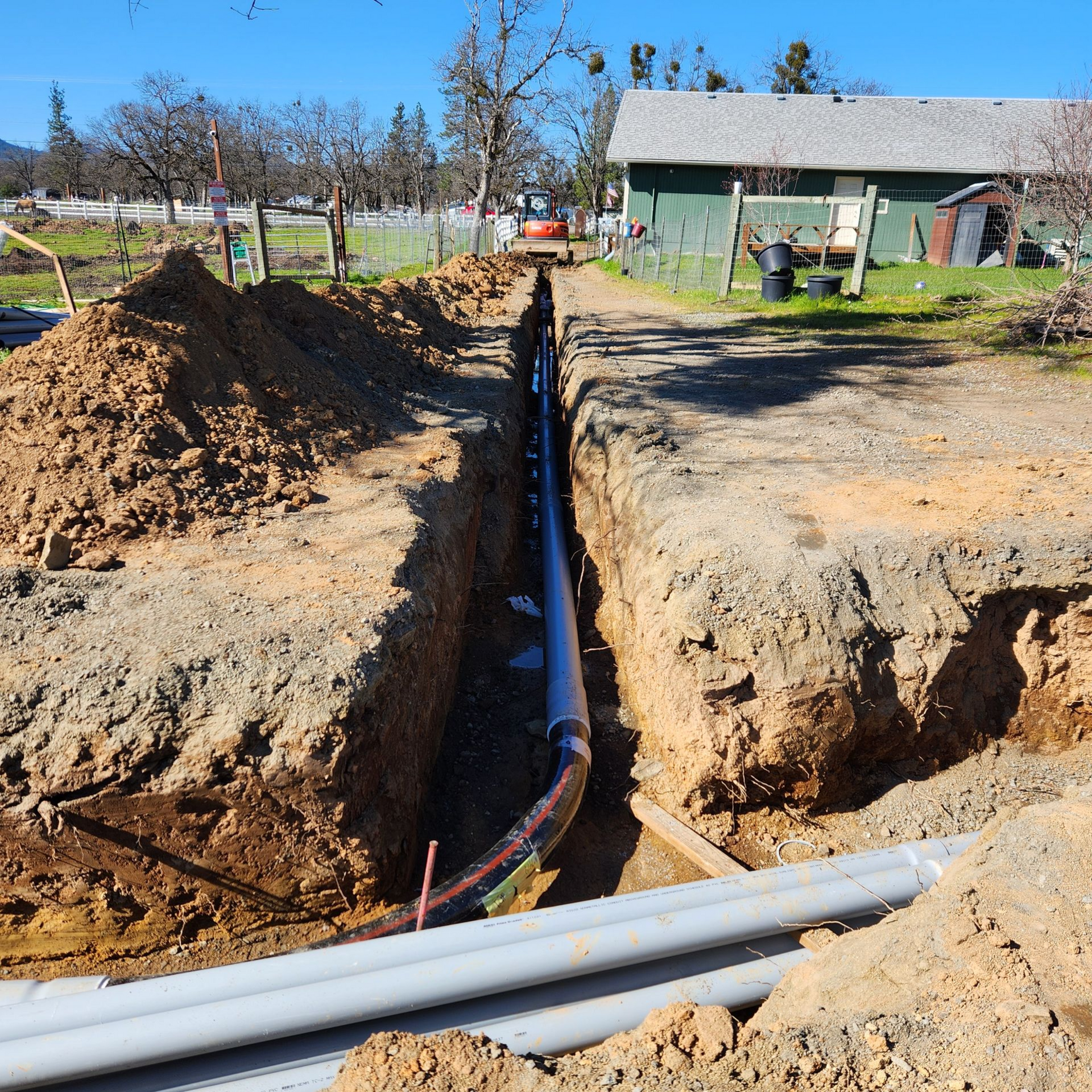 Excavator digging utility trench for water and electrical lines in Southern Oregon