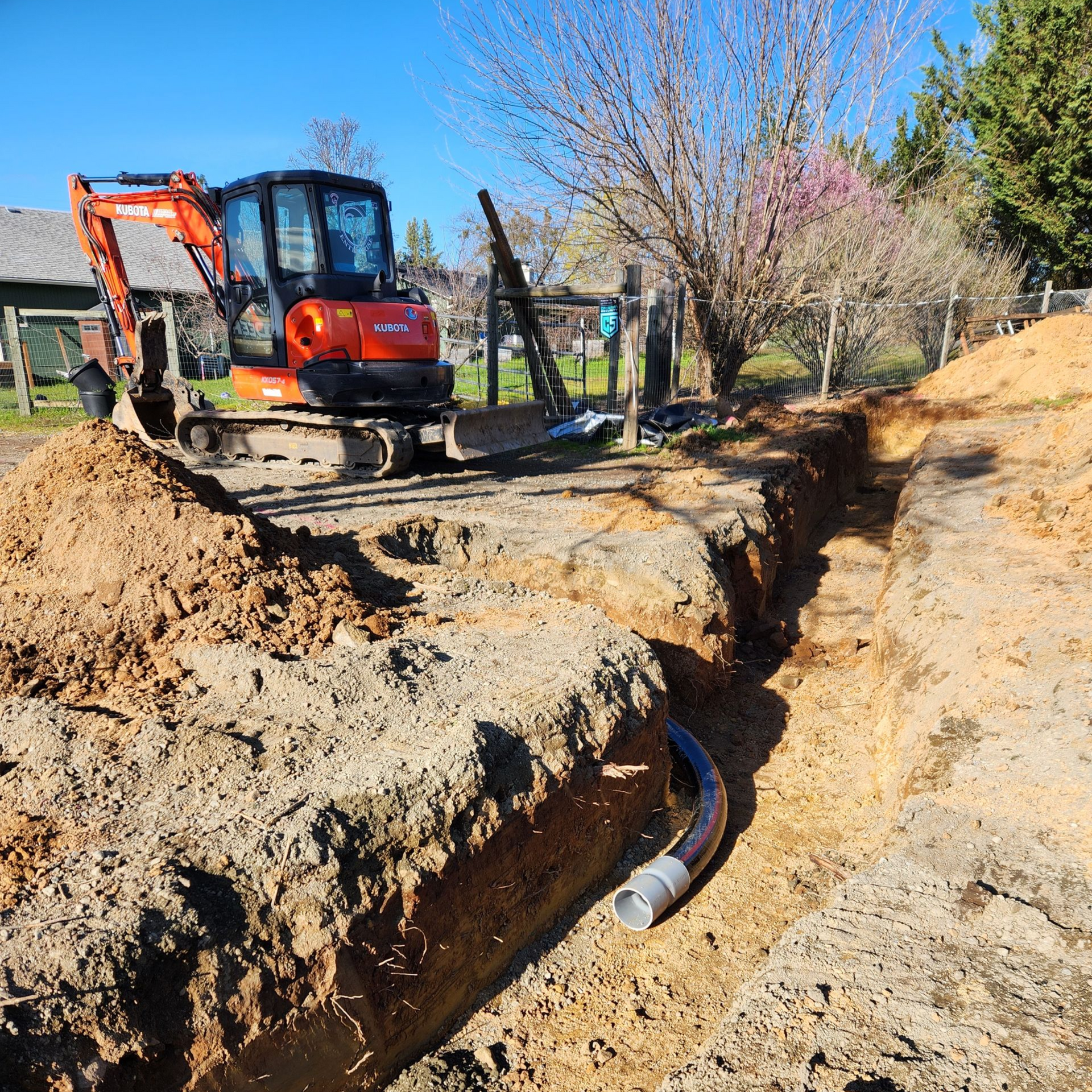 Excavator digging utility trench for water and electrical lines in Medford Oregon