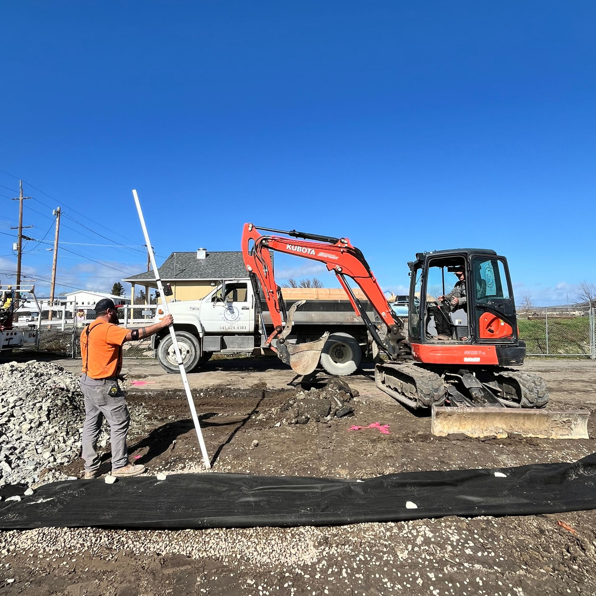 Excavator grading a level house pad for a new home foundation in Medford Oregon