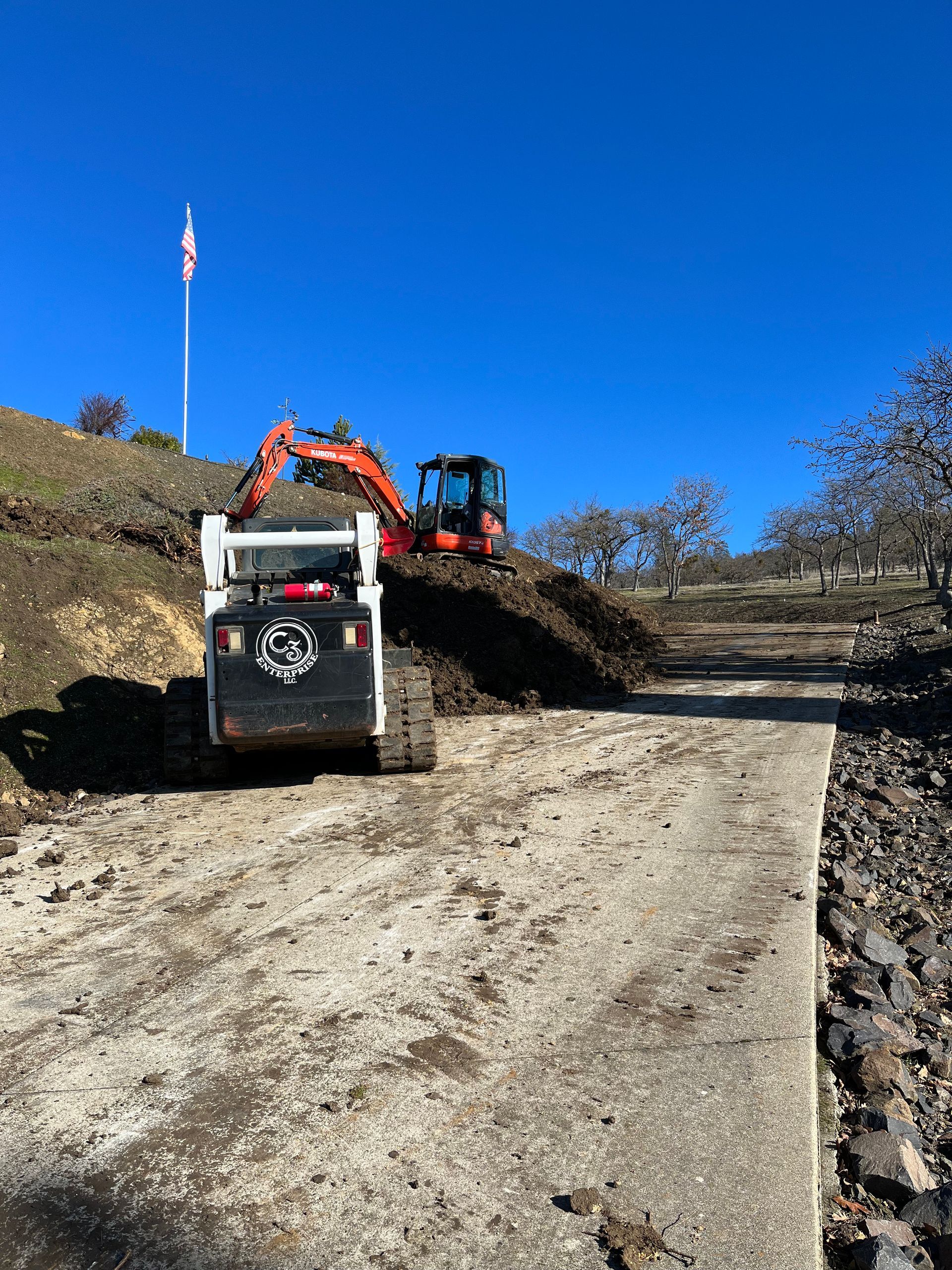 A bulldozer and an excavator are working on a dirt road.