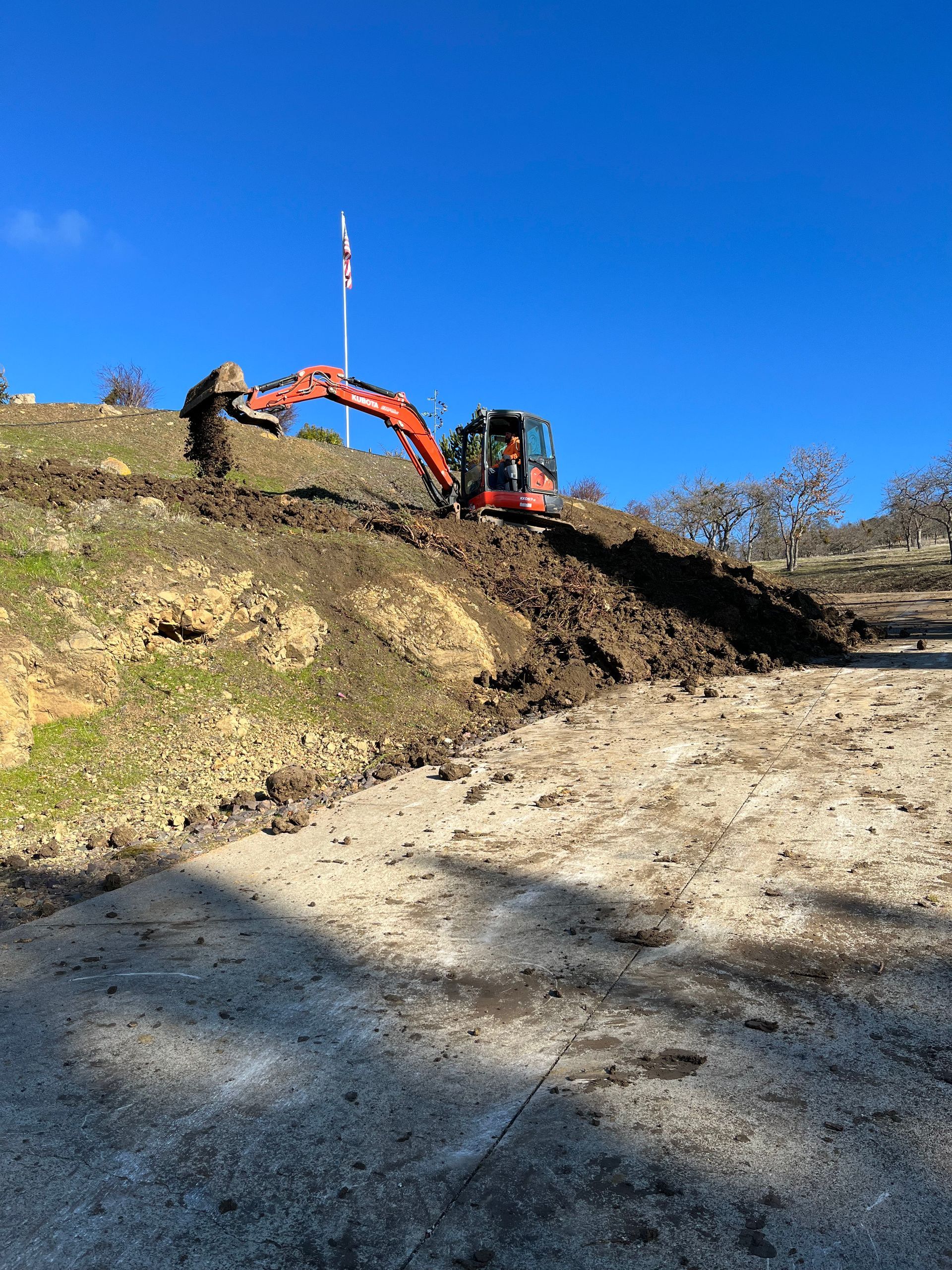 An excavator is digging a hole in the dirt on a hill.
