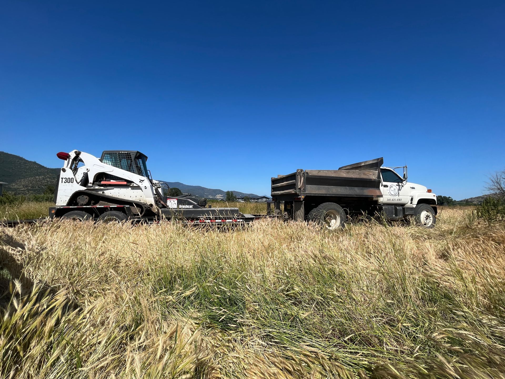 A bulldozer and a dump truck are parked in a field.