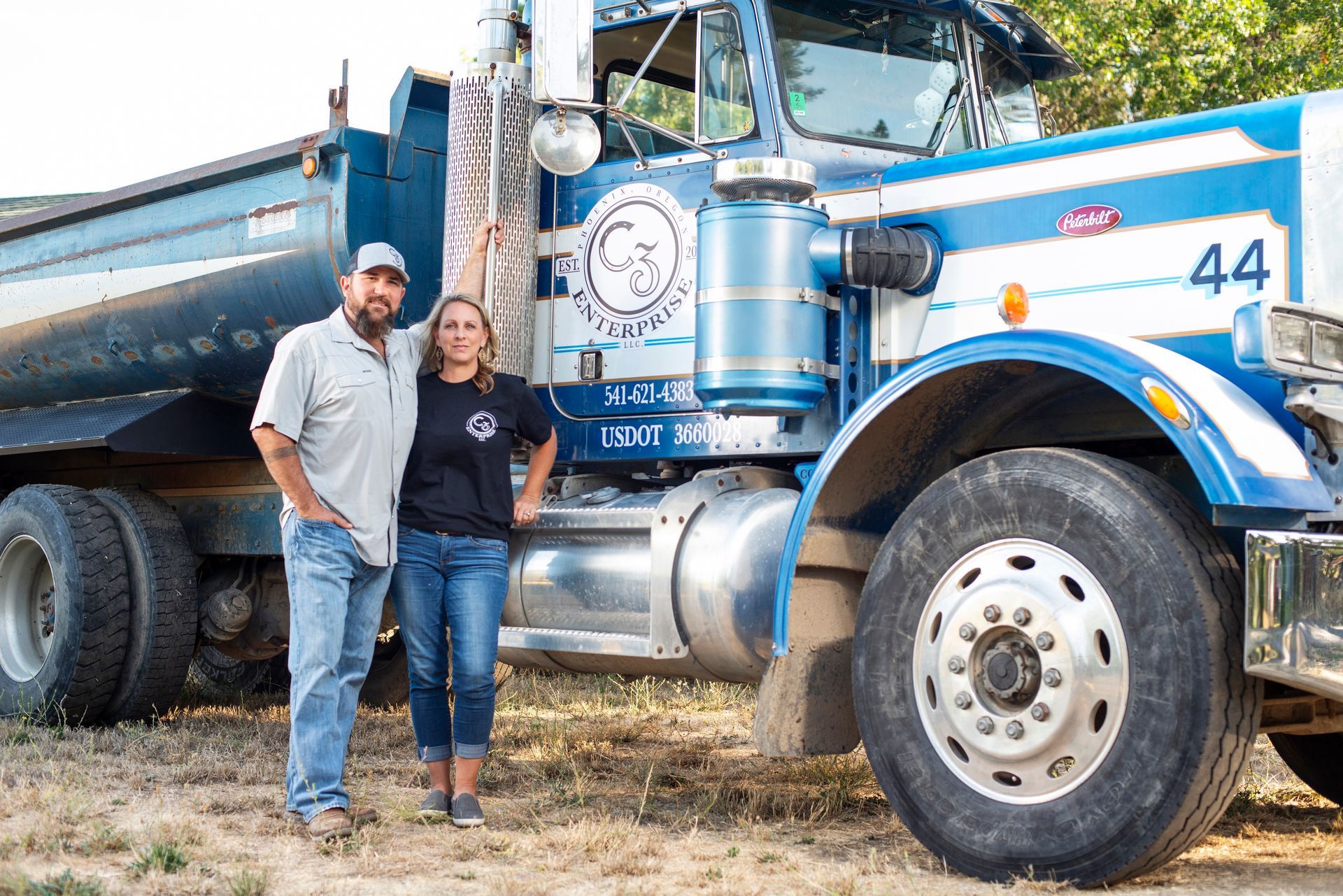 C3 Enterprise owners standing in front of their dump truck in Ashland, Oregon.