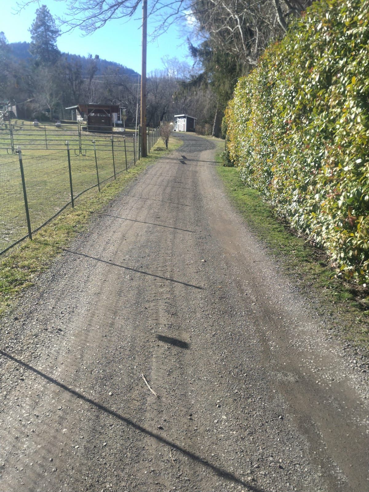 A dirt road with a fence along the side of it