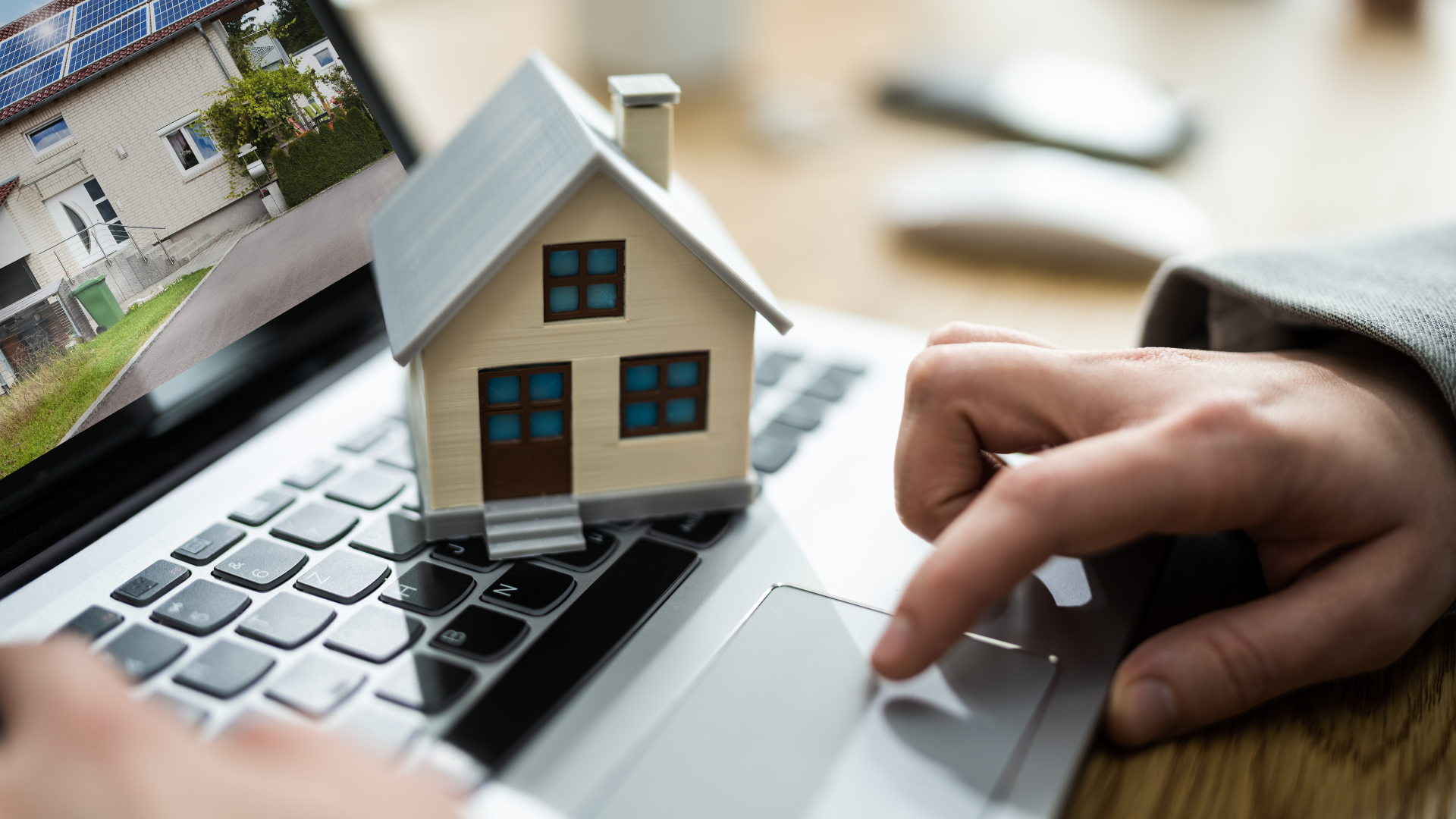 A person is typing on a laptop with a model house on the keyboard.