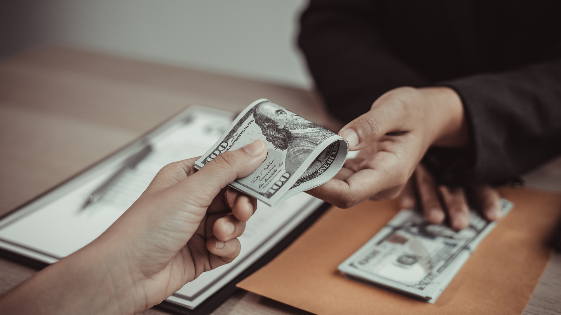 A person is handing a stack of money to another person.