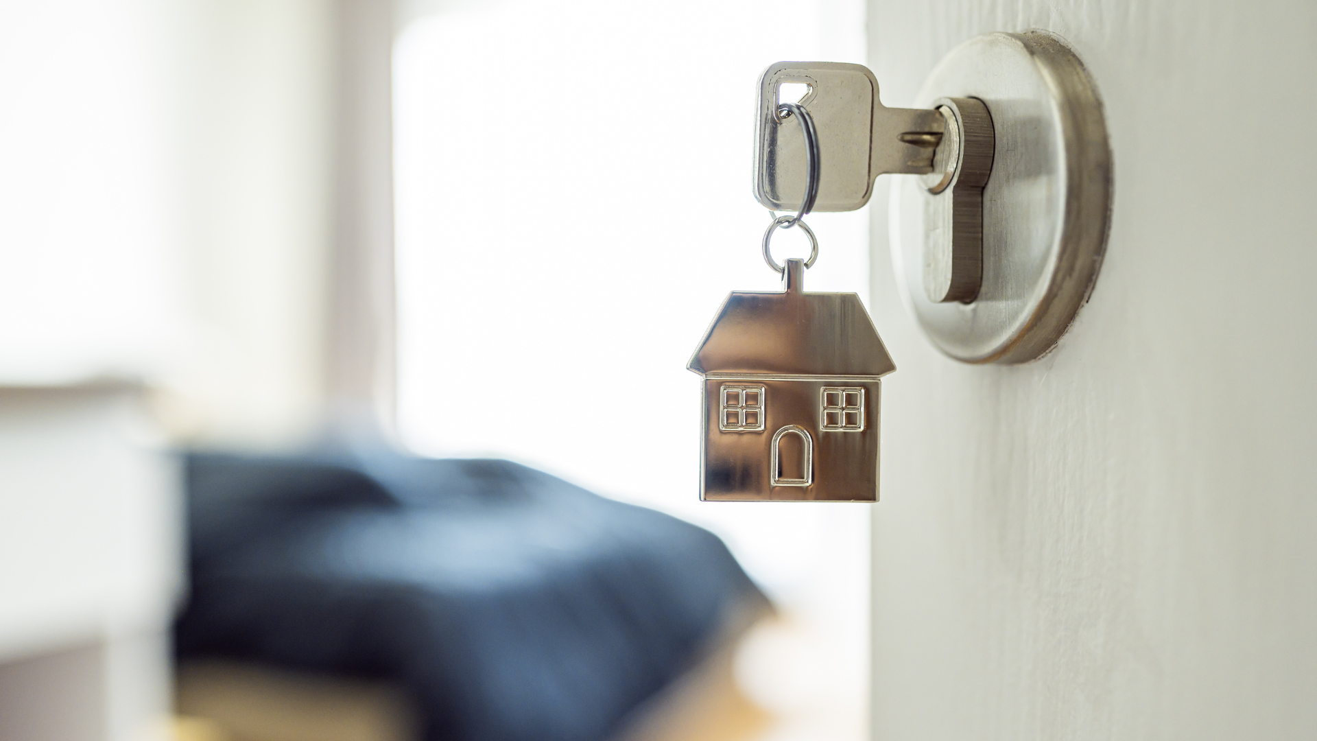 A key with a house keychain attached to it is hanging on a door.