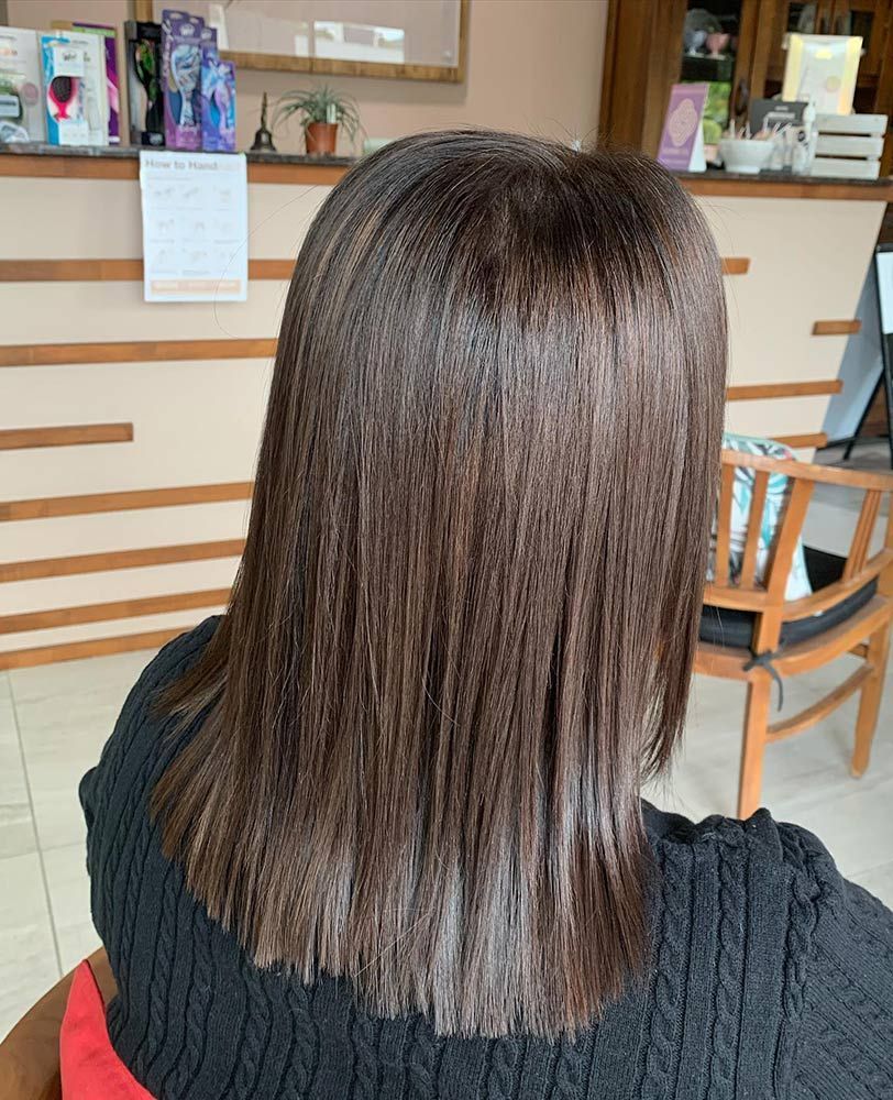 A Woman With Long Brown Hair is Sitting in a Chair in Front of a Counter — Instyle Hair on B in Berserker, QLD