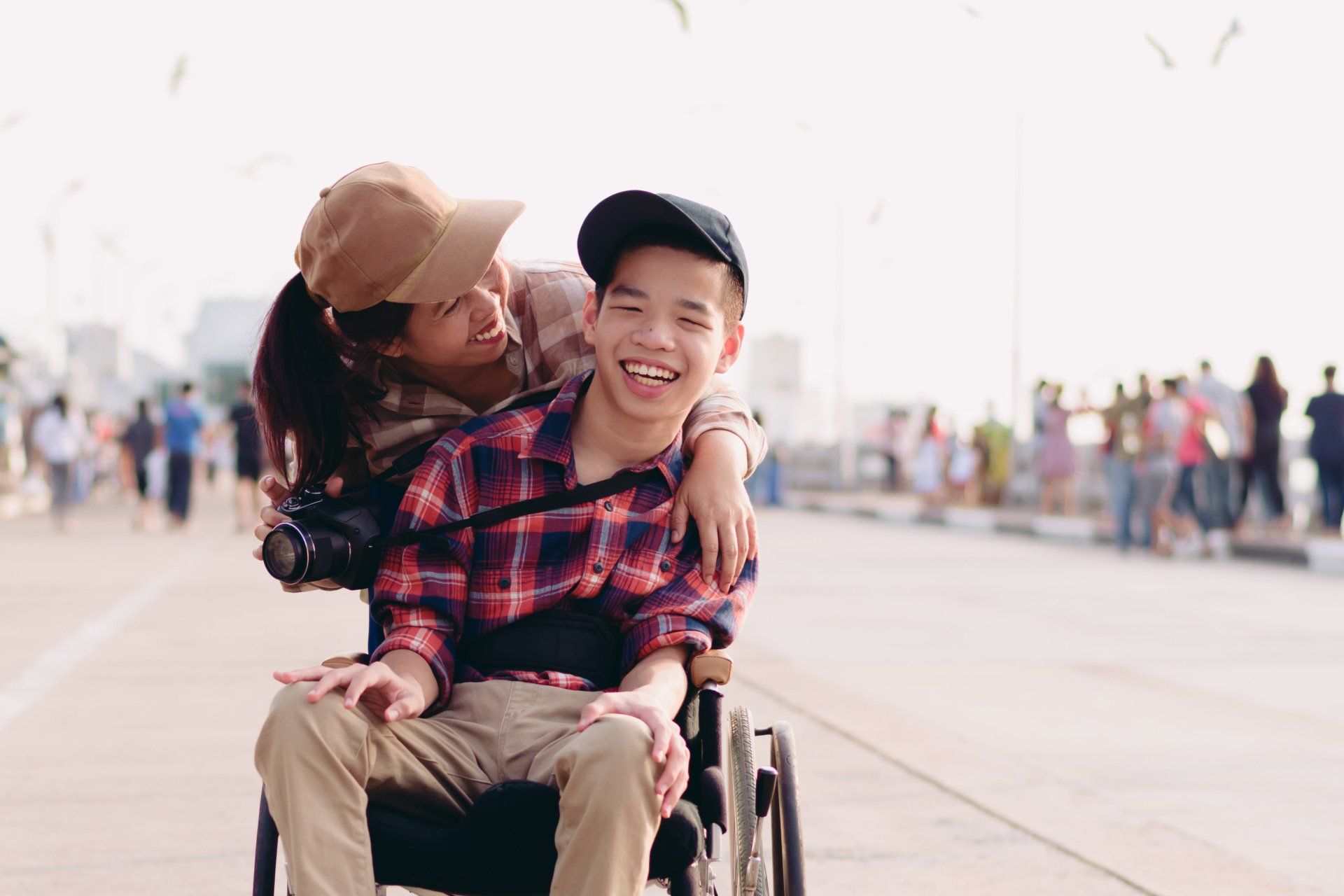 Boy in wheelchair with mom and camera smiling