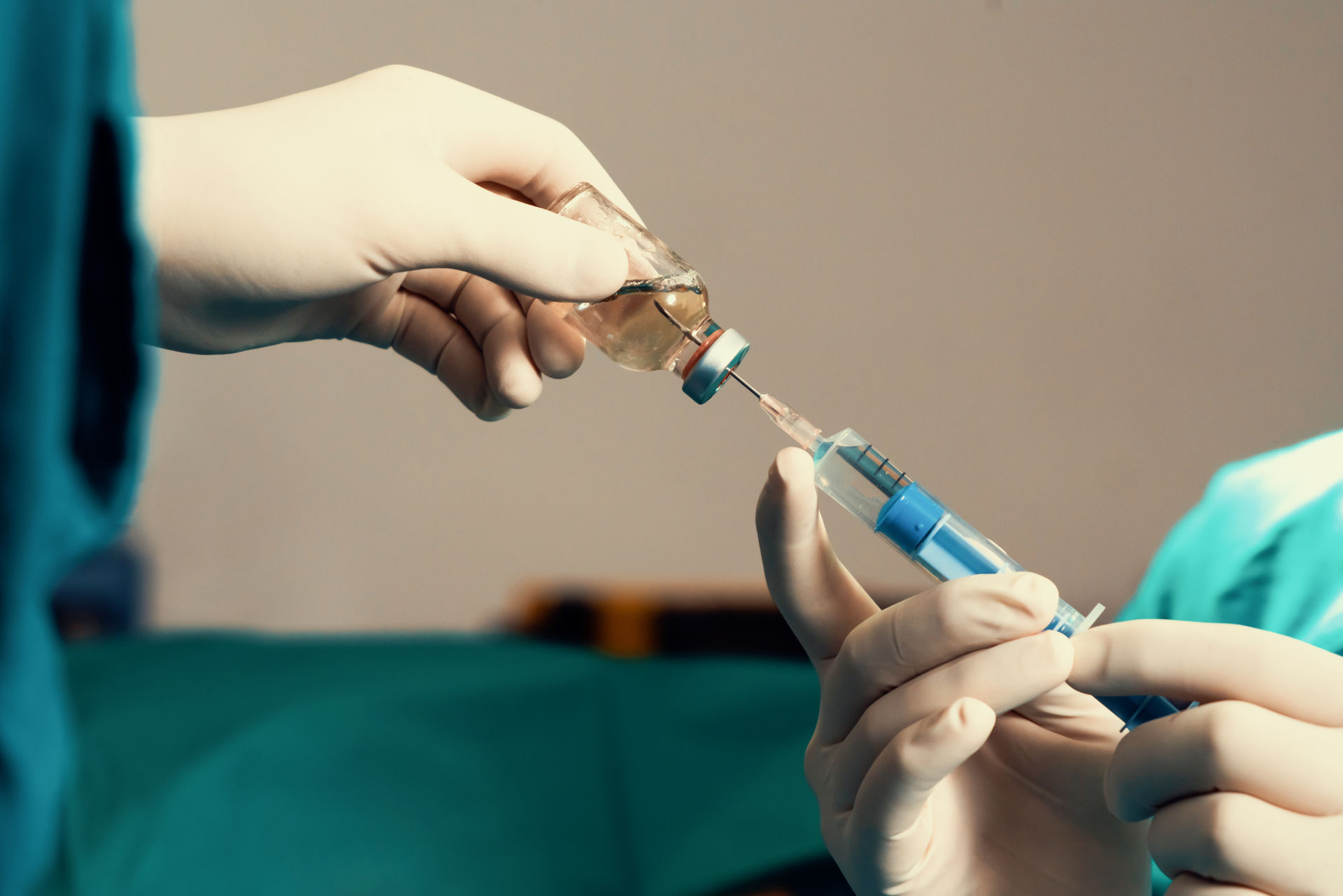 A person is holding a syringe and a bottle of liquid.
