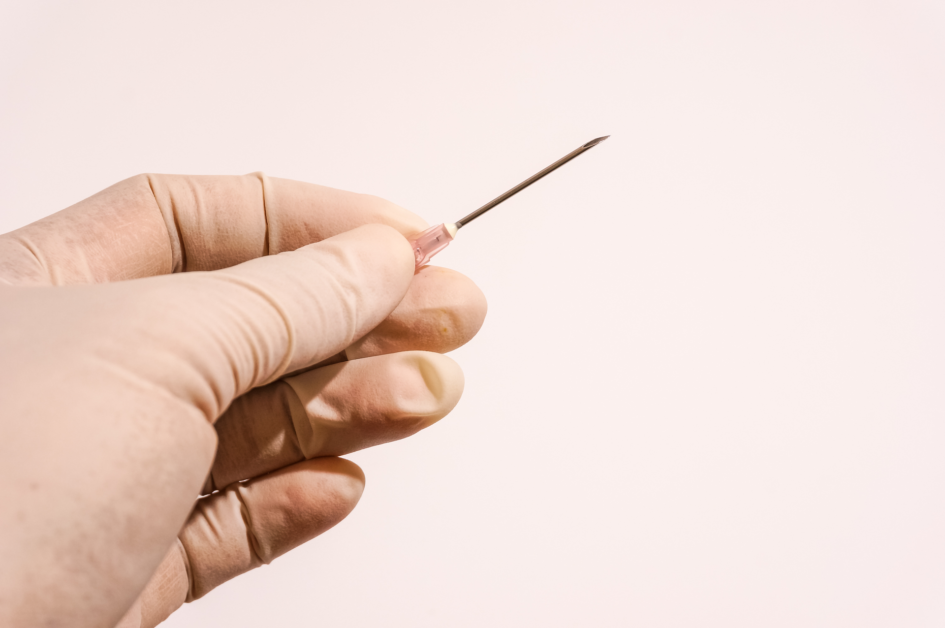A person wearing a glove is holding a needle in their hand.