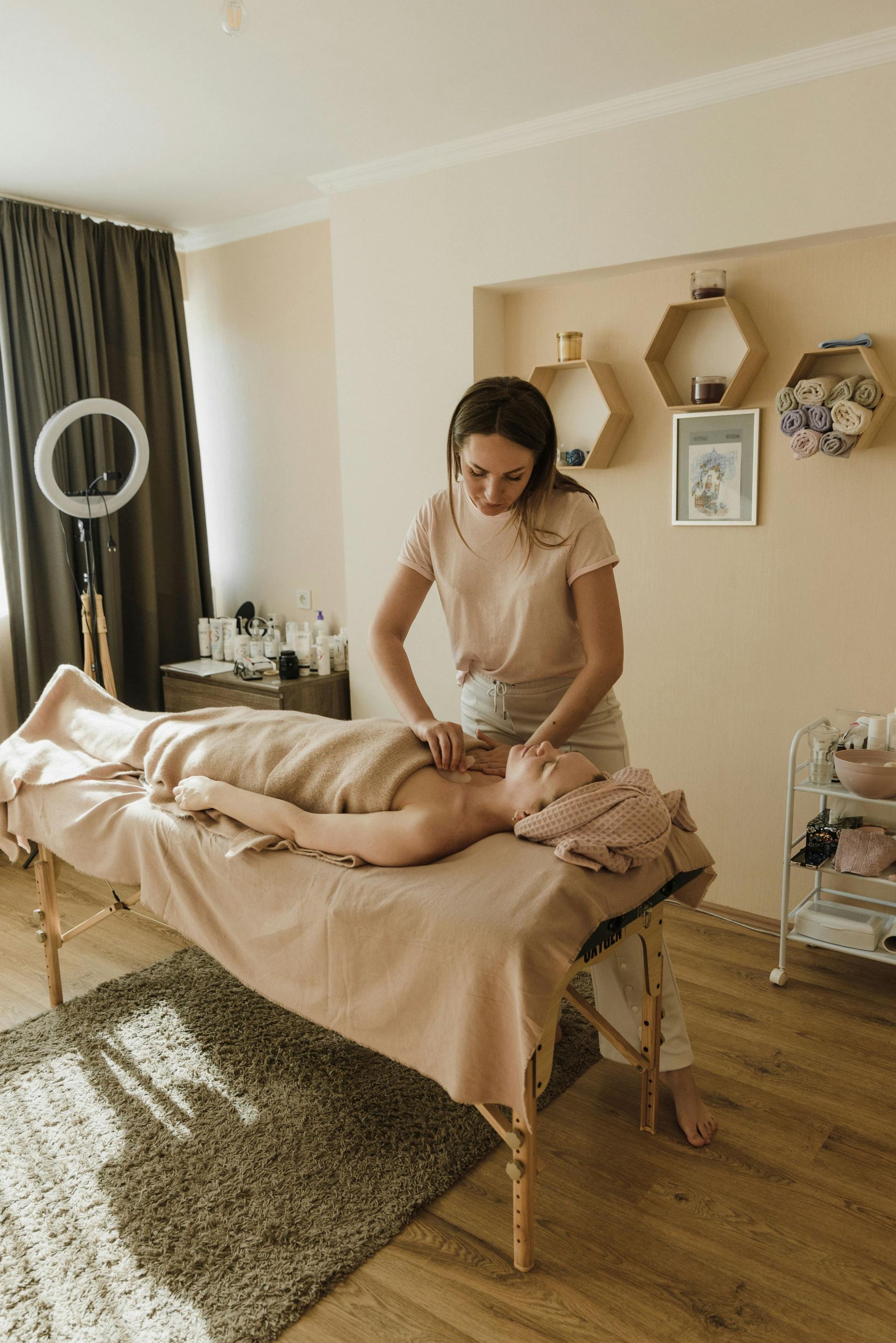 A woman is giving a massage to a woman laying on a massage table.