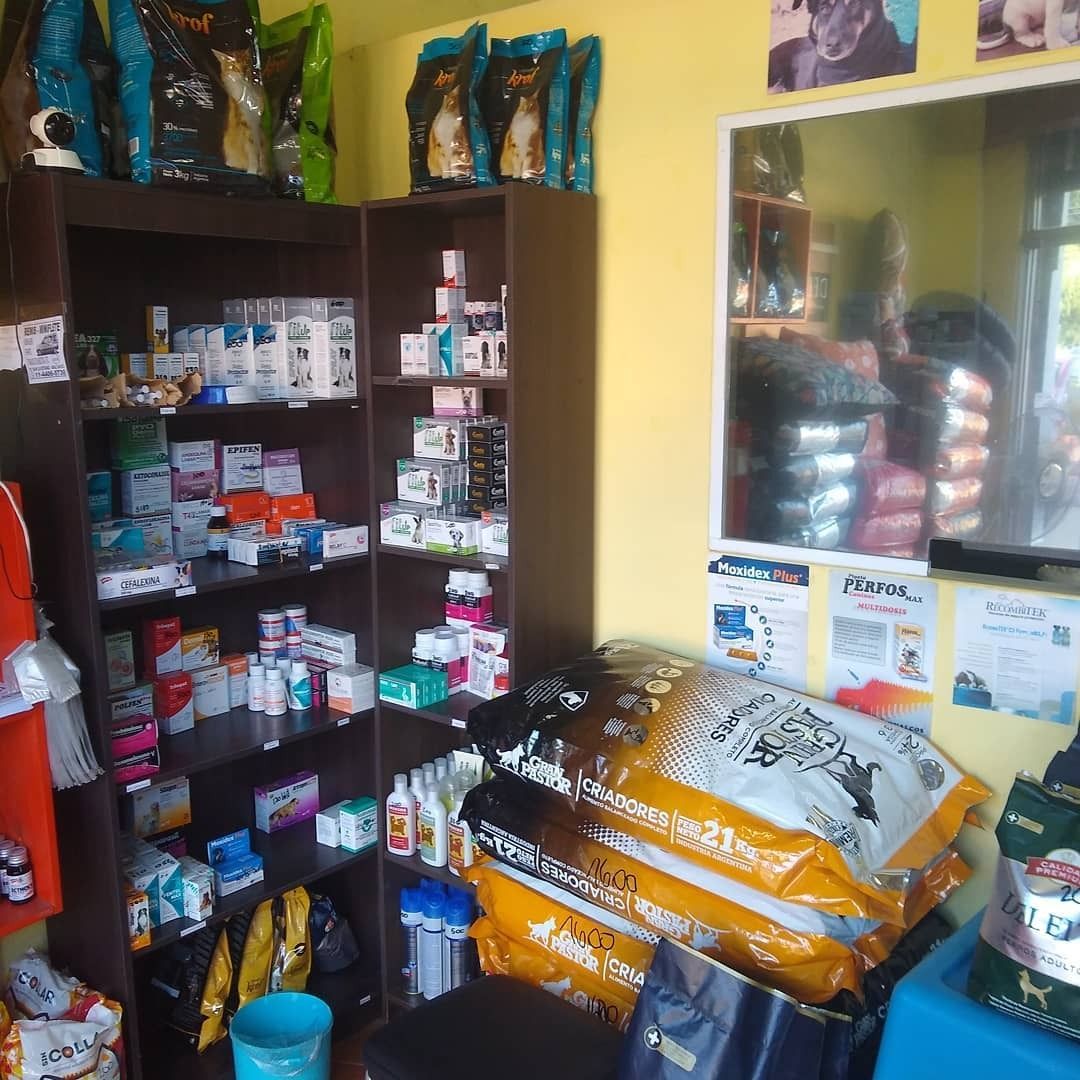 El interior de una tienda de artículos para mascotas, con estantes repletos de medicamentos, bolsas de comida y un espejo que refleja a una persona.