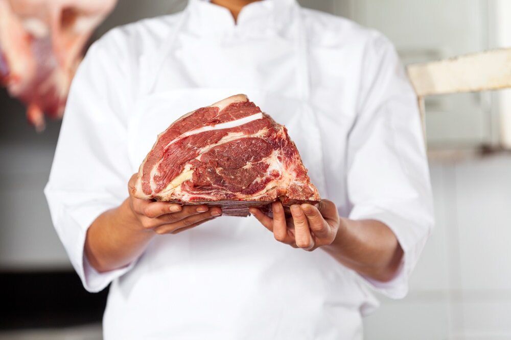 A Butcher is Holding a Large Piece of Raw Meat in His Hands  — Scotto's Food Logistics in Mitchell, ACT