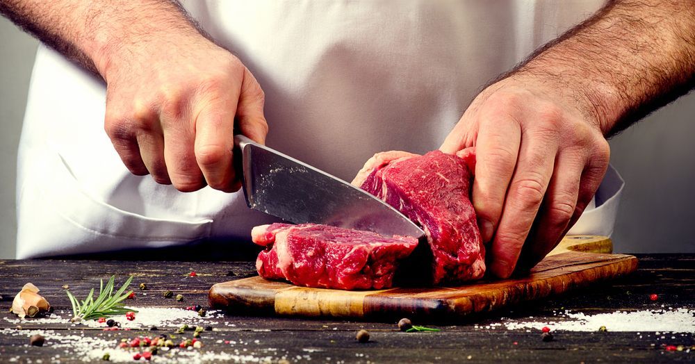 A Man is Cutting a Piece of Meat on a Cutting Board — Scotto's Food Logistics in Mitchell, ACT