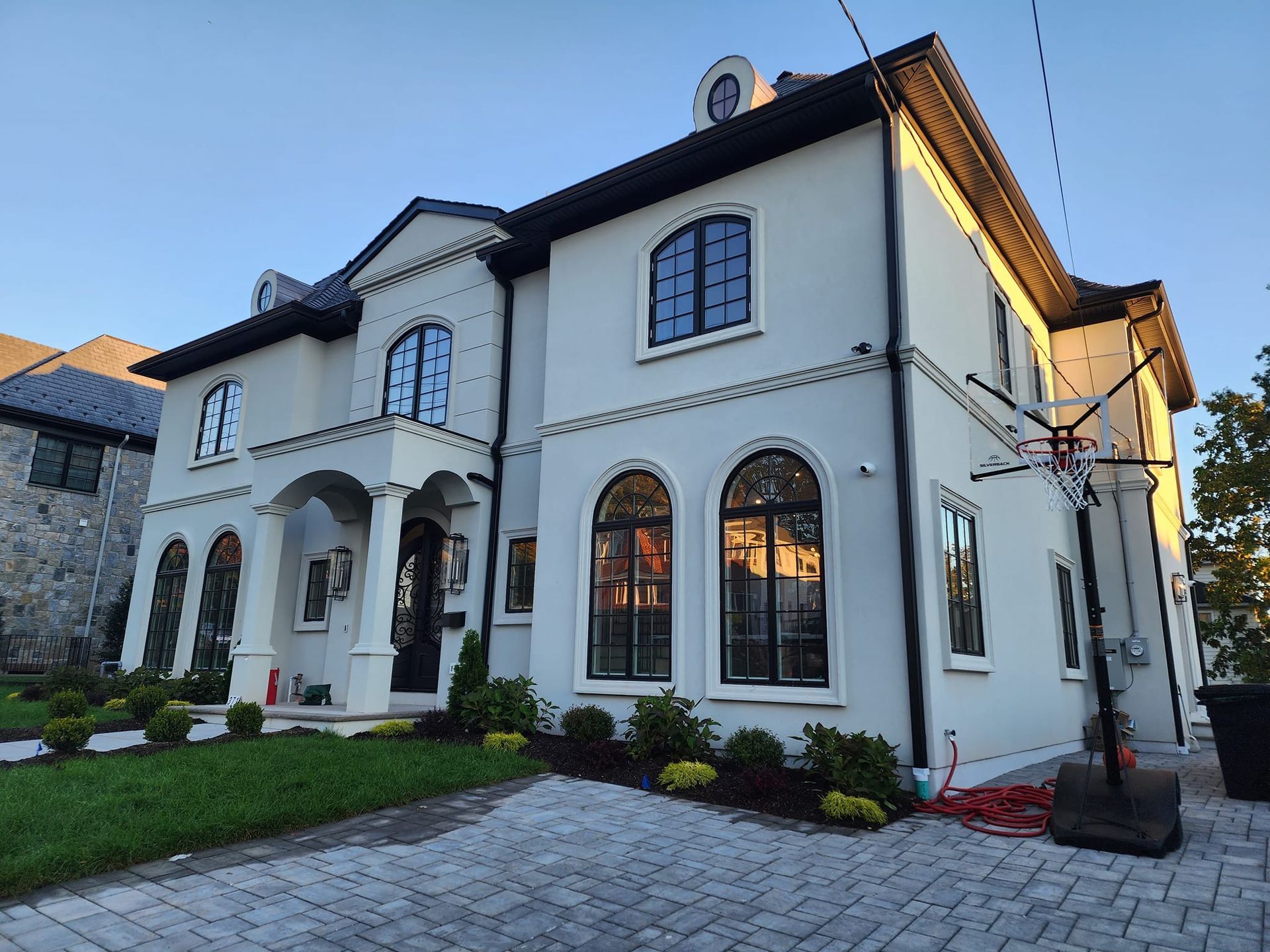 a large white house with a lot of windows and a brick driveway .