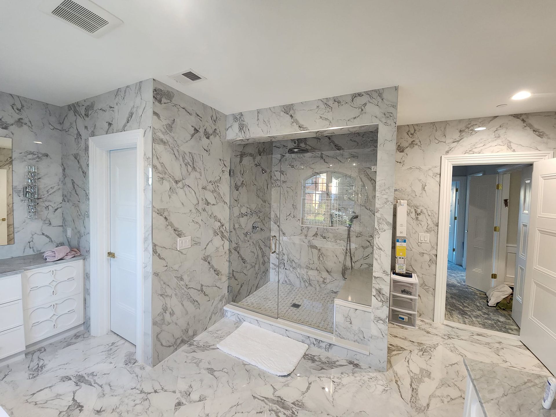 a bathroom with marble tiles and a walk in shower .