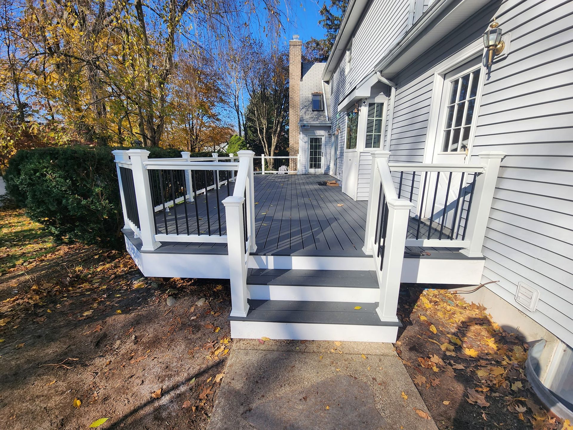 a white house with a deck and stairs in front of it .