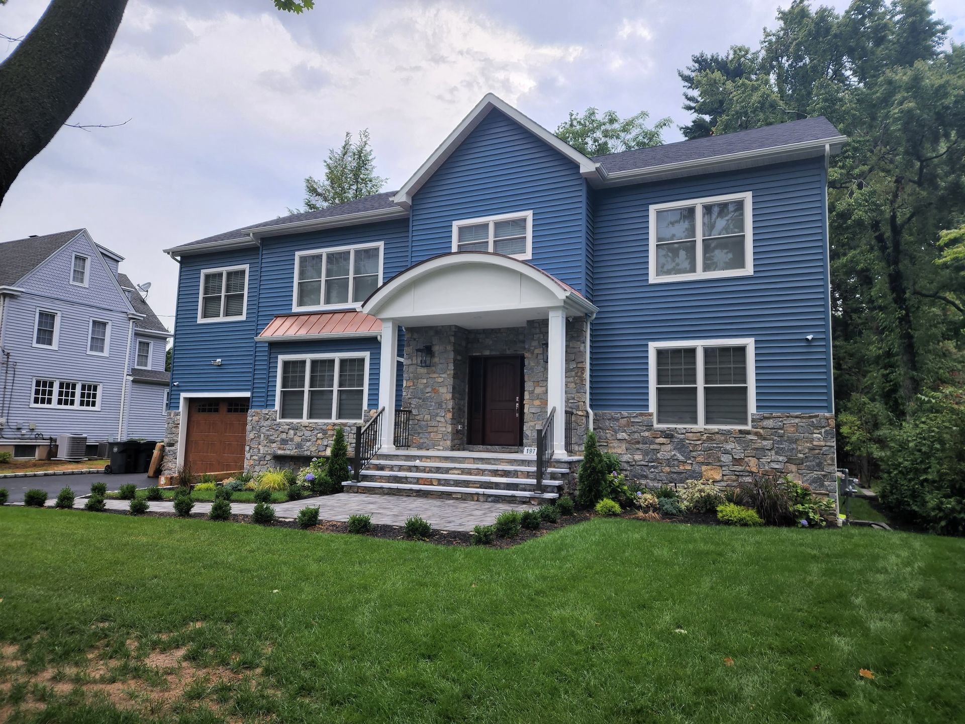 a large blue house with white trim and a stone facade