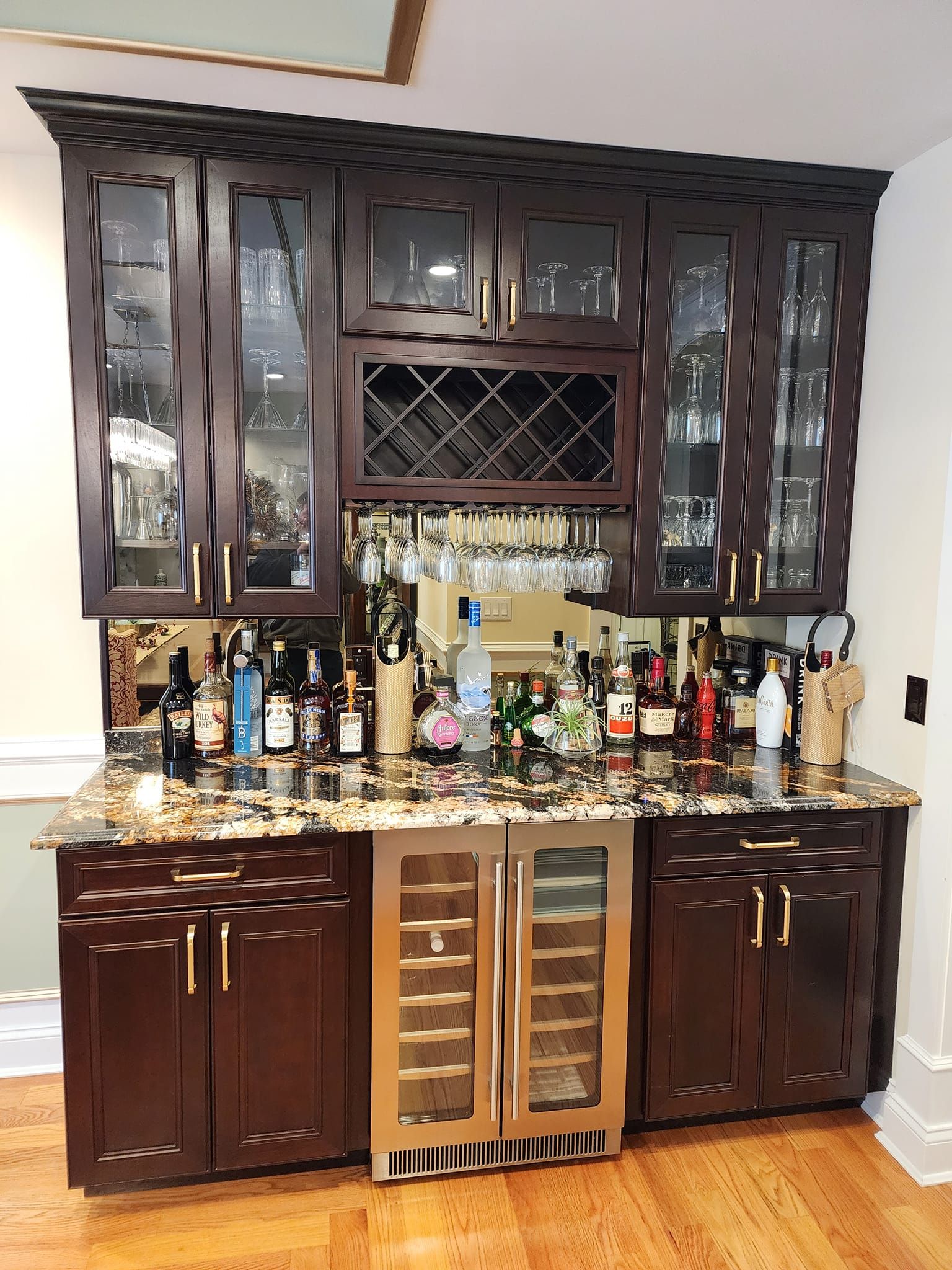 a bar with bottles of liquor and glasses on it in a kitchen .