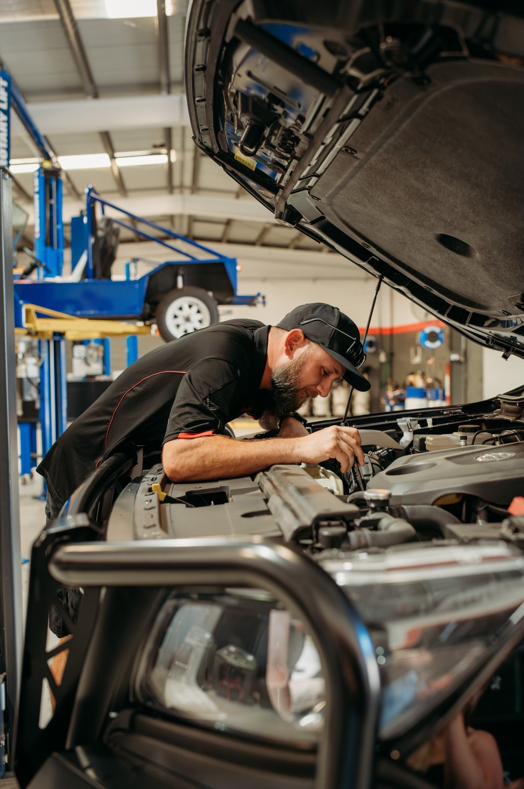 A Man Working On A Car Engine In A Garage — Signature Mechanical In South Gladstone, QLD