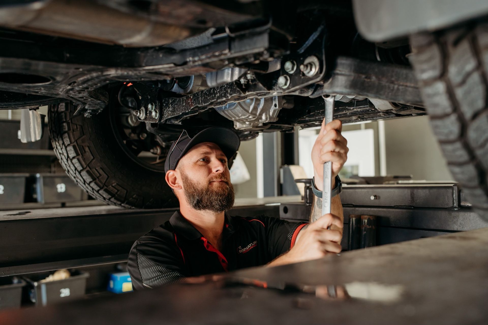 A Man Is Working On The Underside Of A Car In A Garage — Signature Mechanical In South Gladstone, QLD