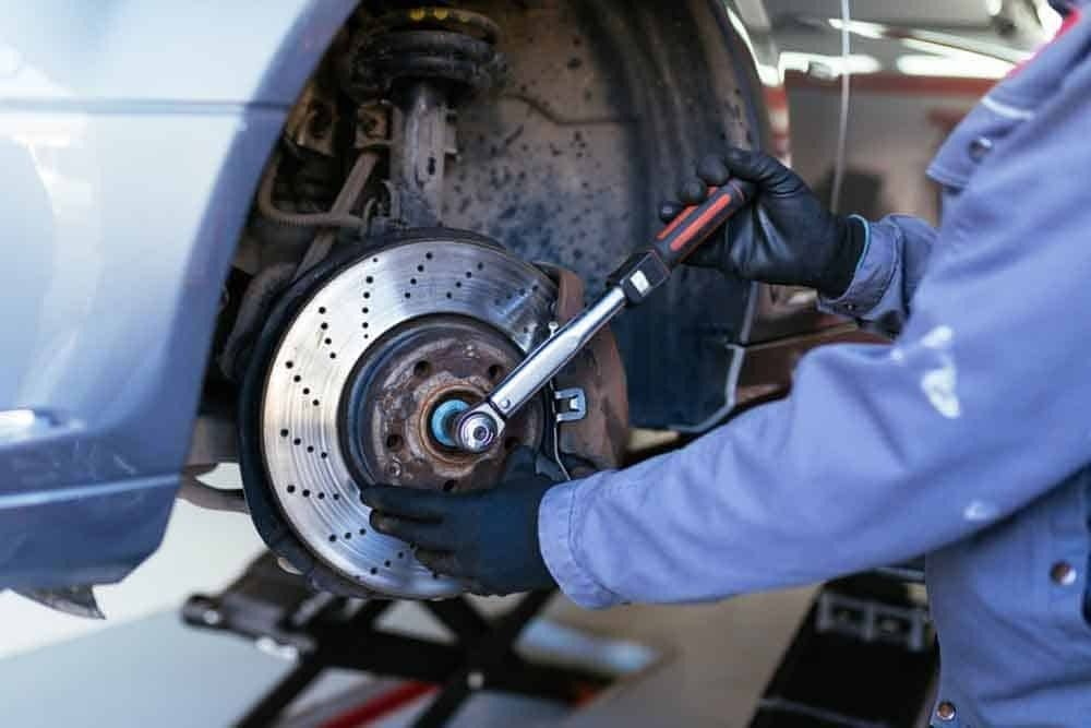 A Man Is Fixing A Brake Disc On A Car With A Wrench — Signature Mechanical In South Gladstone, QLD