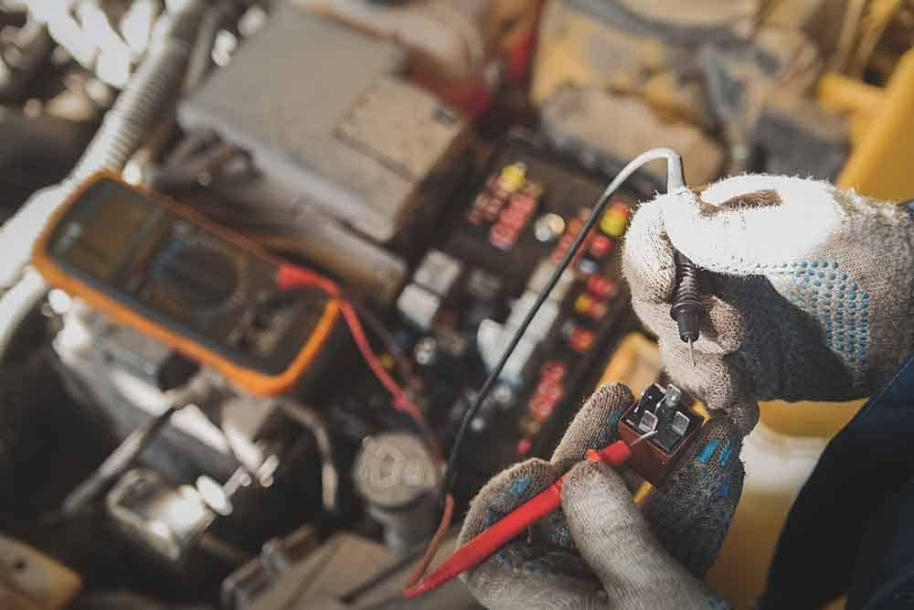 A Man Is Working On A Car With A Multimeter — Signature Mechanical In South Gladstone, QLD