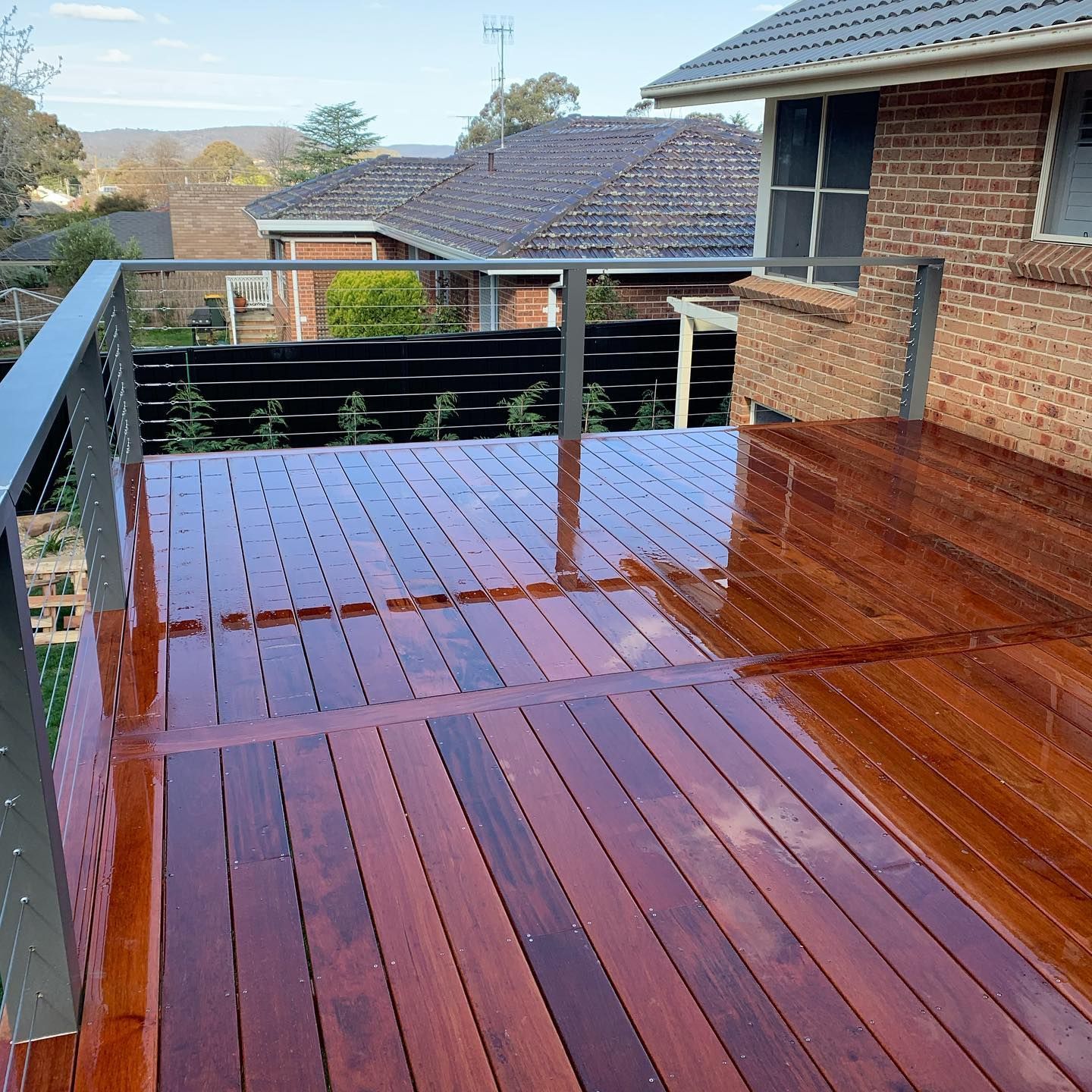 Wooden Deck With Shiny Finish, Brick House in Background — J&C Quality Construction in Goulburn, NSW