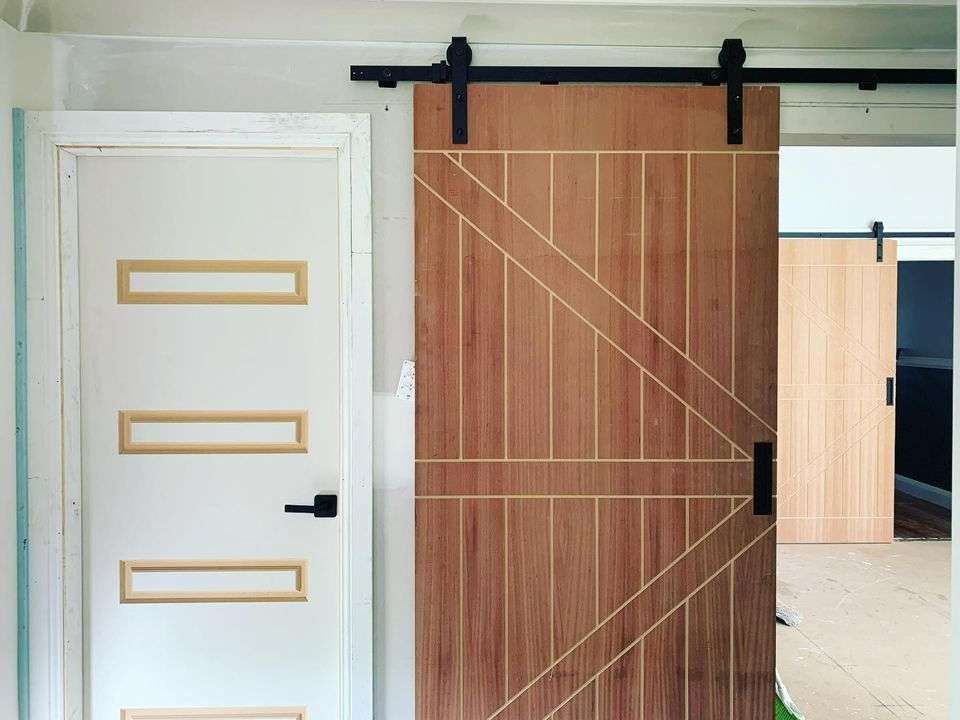 A Wooden Barn Door Slides Open Revealing Another Door — J&C Quality Construction in Goulburn, NSW