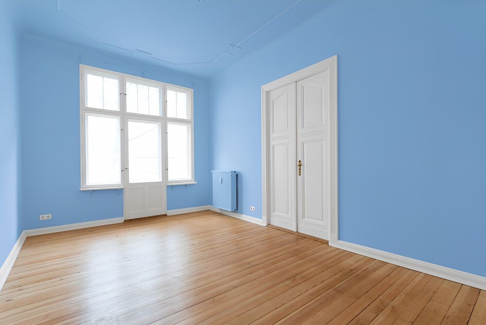 An Empty Room With Blue Walls And Wooden Floors — J&C Quality Construction in Goulburn, NSW