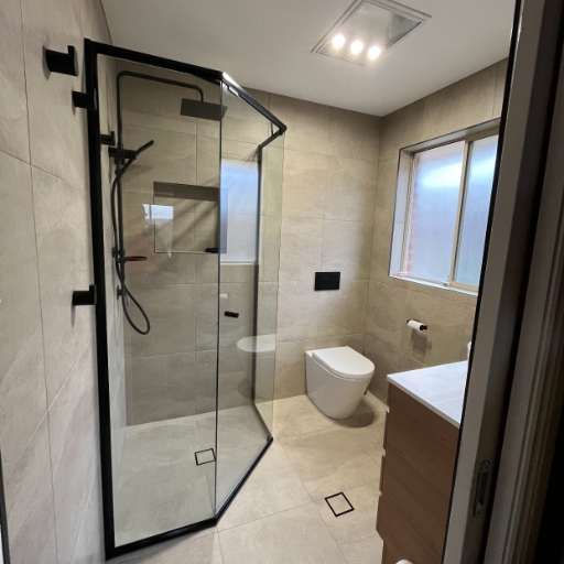 A Bathroom With A Toilet, Sink, Shower And Window — J&C Quality Construction in Goulburn, NSW