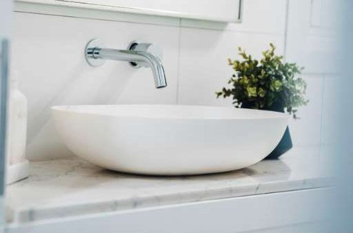A White Sink Is Sitting On A Counter In A Bathroom Next To A Plant — J&C Quality Construction in Goulburn, NSW