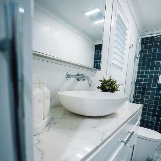 A Bathroom With A Sink, Toilet And Mirror — J&C Quality Construction in Goulburn, NSW