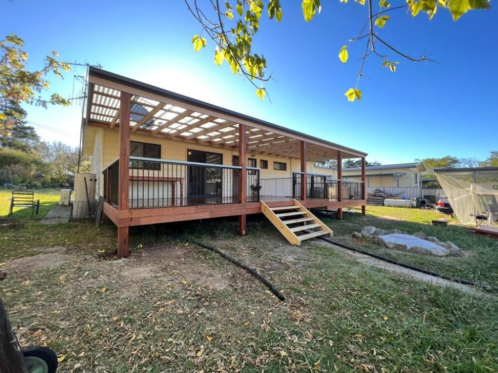 Yellow House With a Wooden Deck and Pergola — J&C Quality Construction in Goulburn, NSW