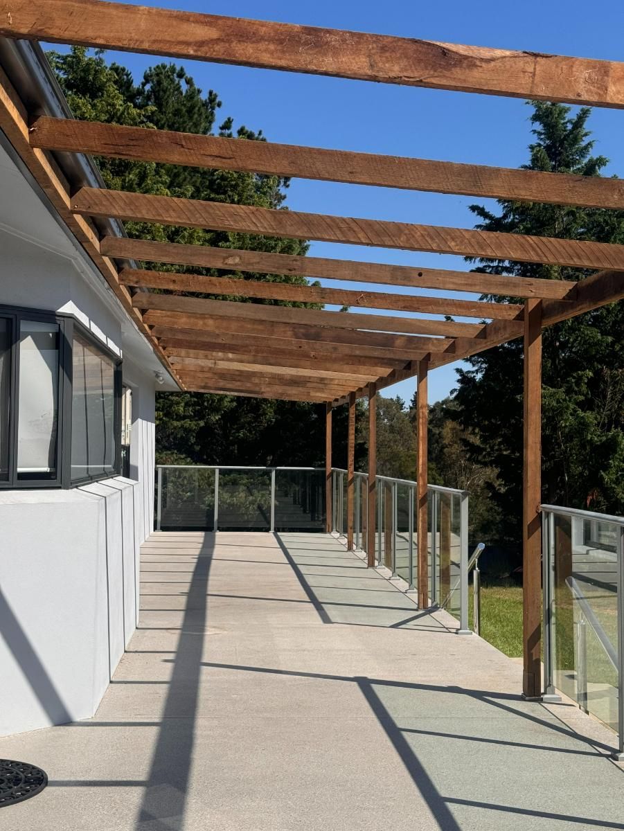 Wooden Pergola Over a Concrete Patio With Glass Railing — J&C Quality Construction in Goulburn, NSW