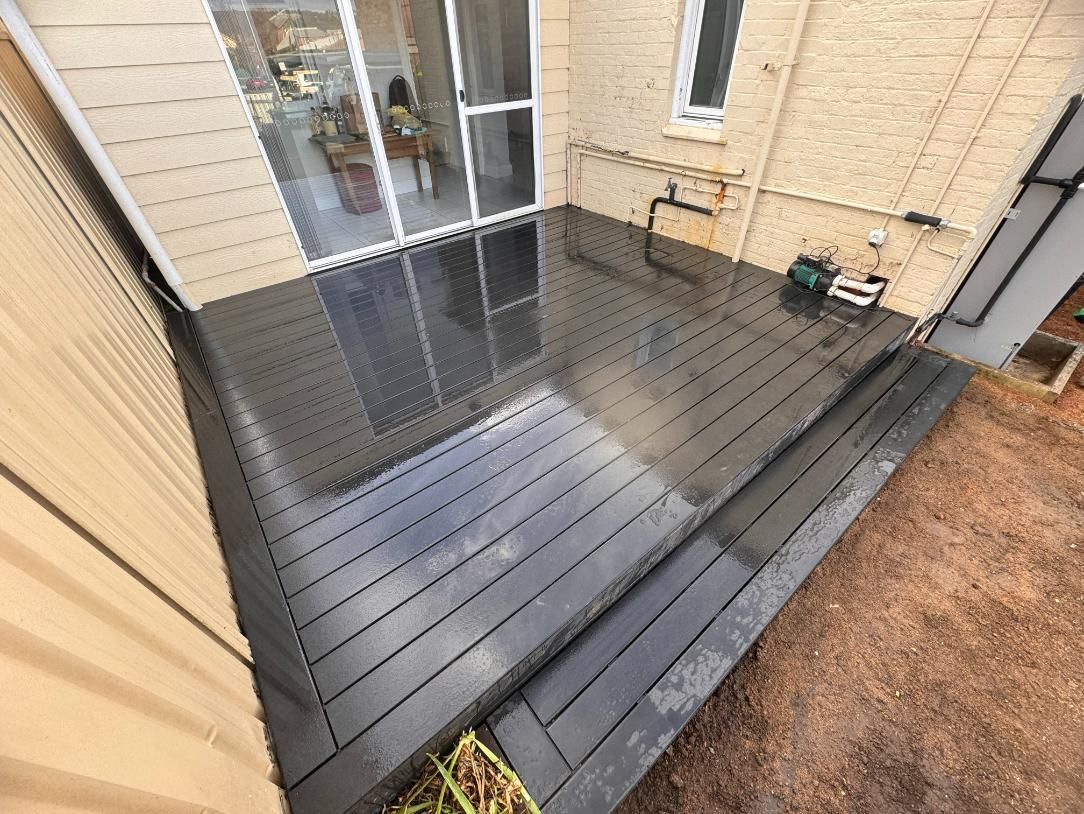 Black Wooden Deck Attached to a Light Brown Building — J&C Quality Construction in Goulburn, NSW