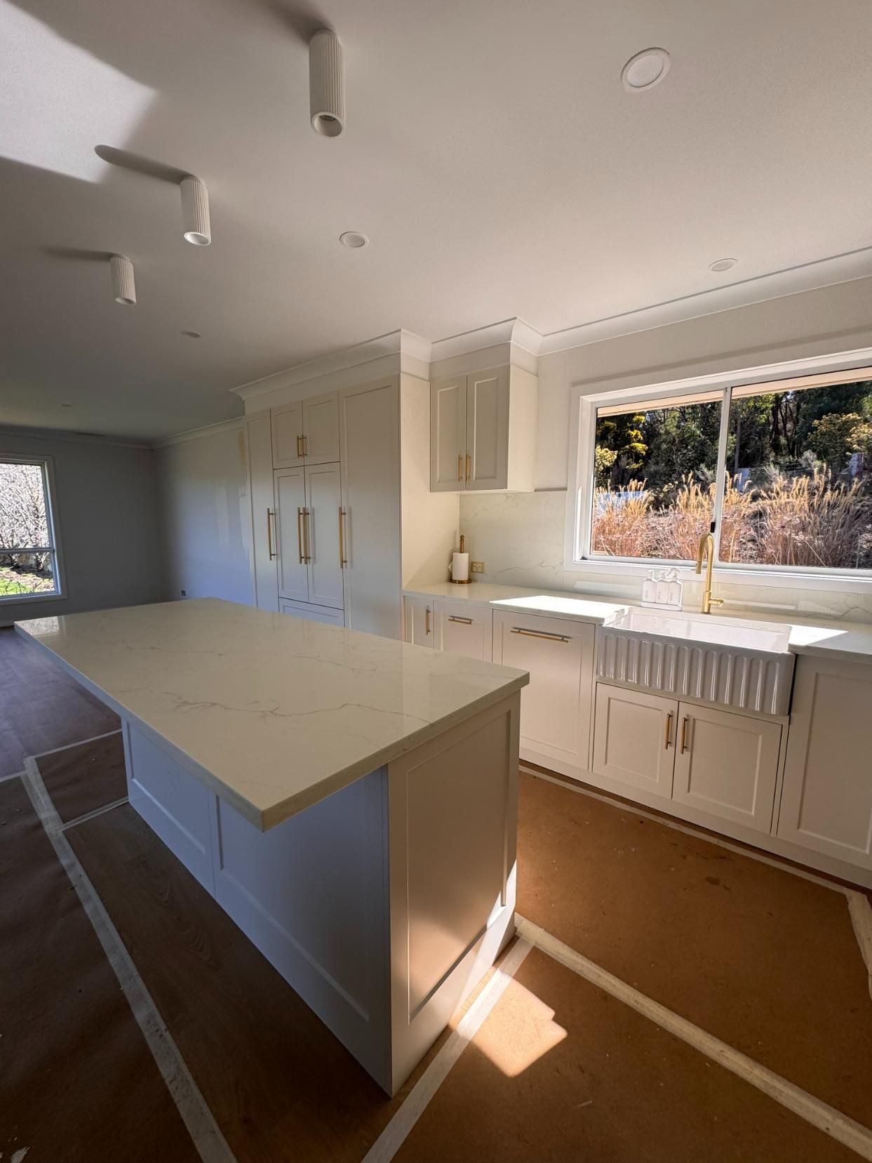 White Kitchen With Island, Cabinets, and a Window — J&C Quality Construction in Bowral, NSW
